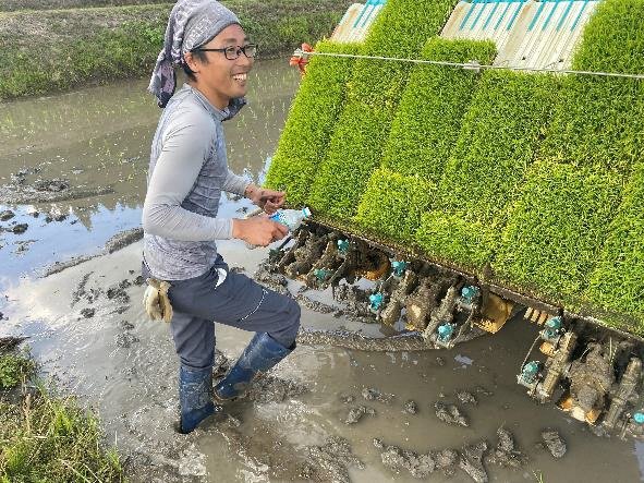 田植機の前で笑顔の矢代耕太さん